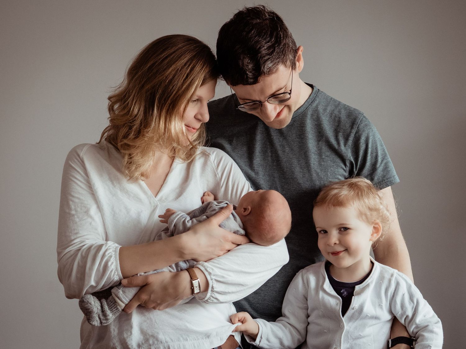 A series of intimate black and white family portraits showing tender moments between parents and their young child.