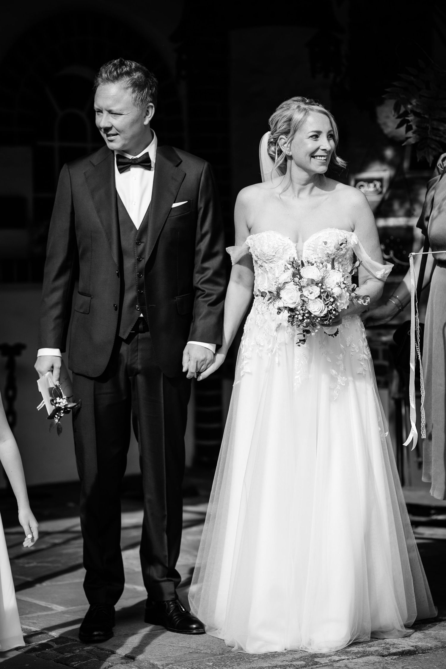 Bride and groom walking hand in hand smiling after their wedding ceremony in black and white.