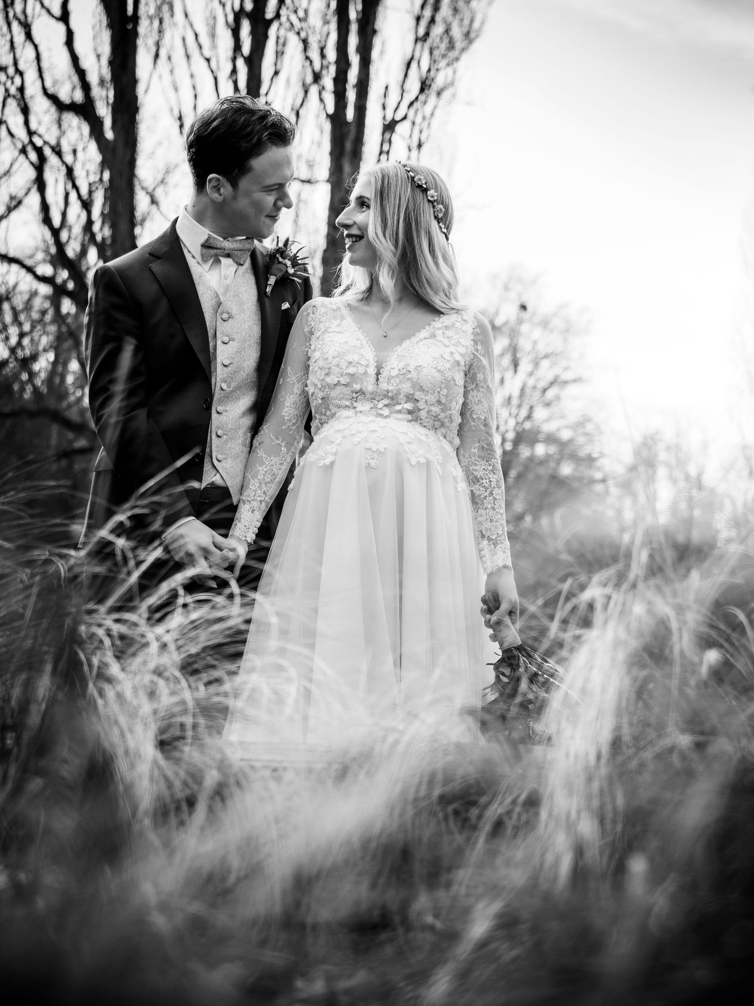 Bride and groom share a romantic moment in a field, black and white wedding photo.