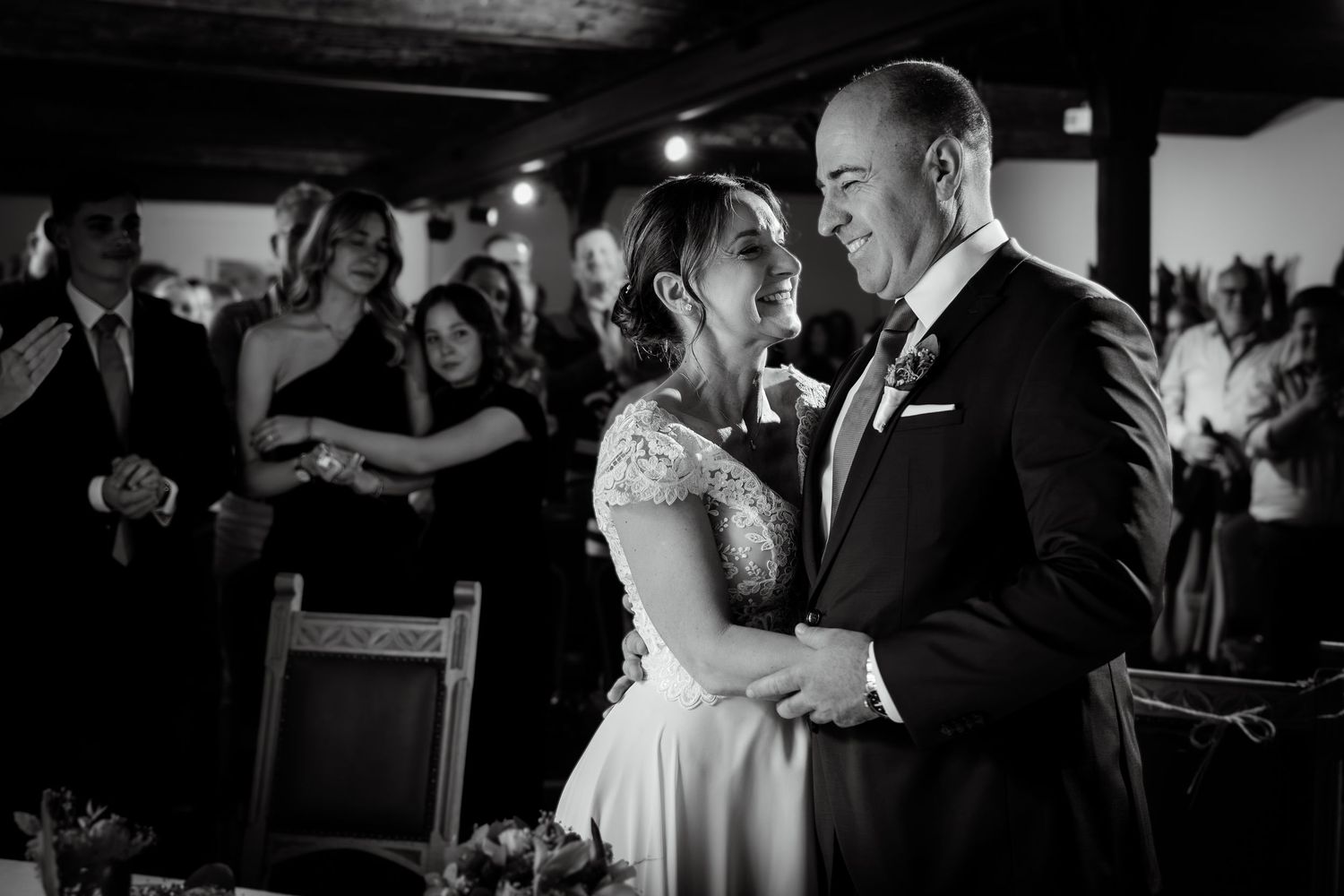 Black and white photo of a smiling bride and groom sharing a tender moment during their wedding reception.