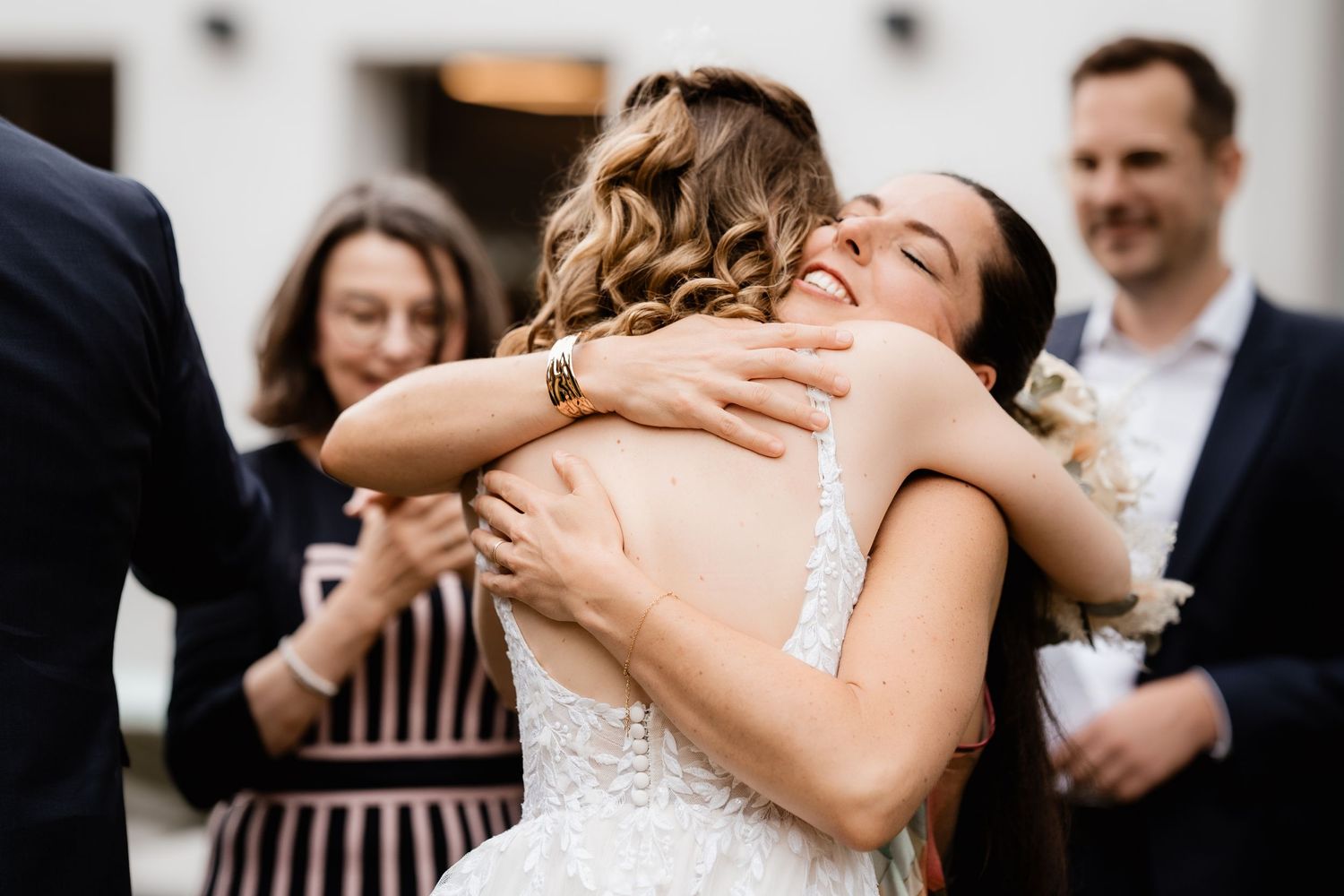 Two brides share a joyful embrace at their wedding celebration outdoors.
