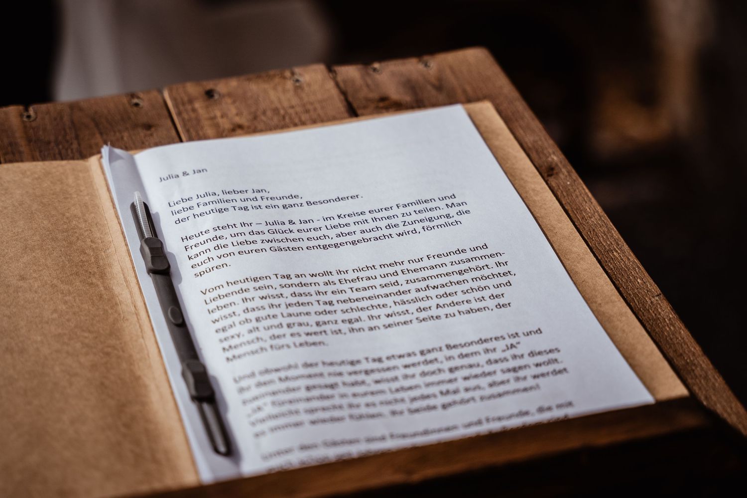 Handwritten wedding speech letter resting on a rustic wooden lectern during a ceremony.