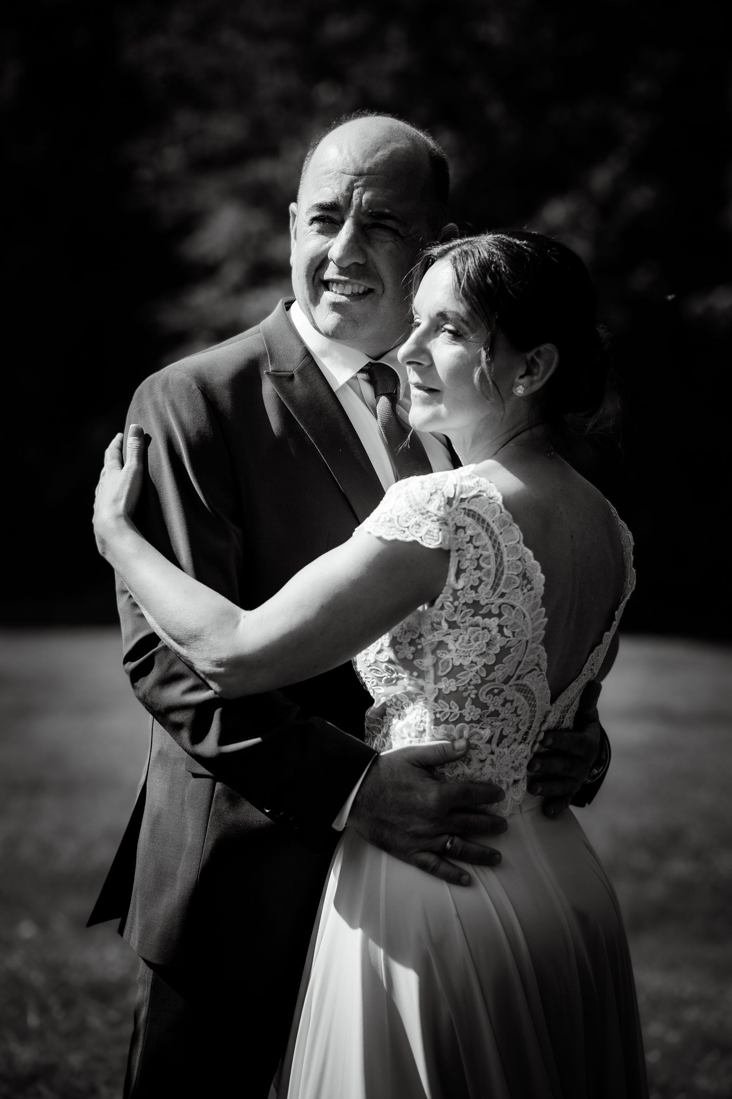 Black and white portrait of smiling bride and groom embracing outdoors on their wedding day.