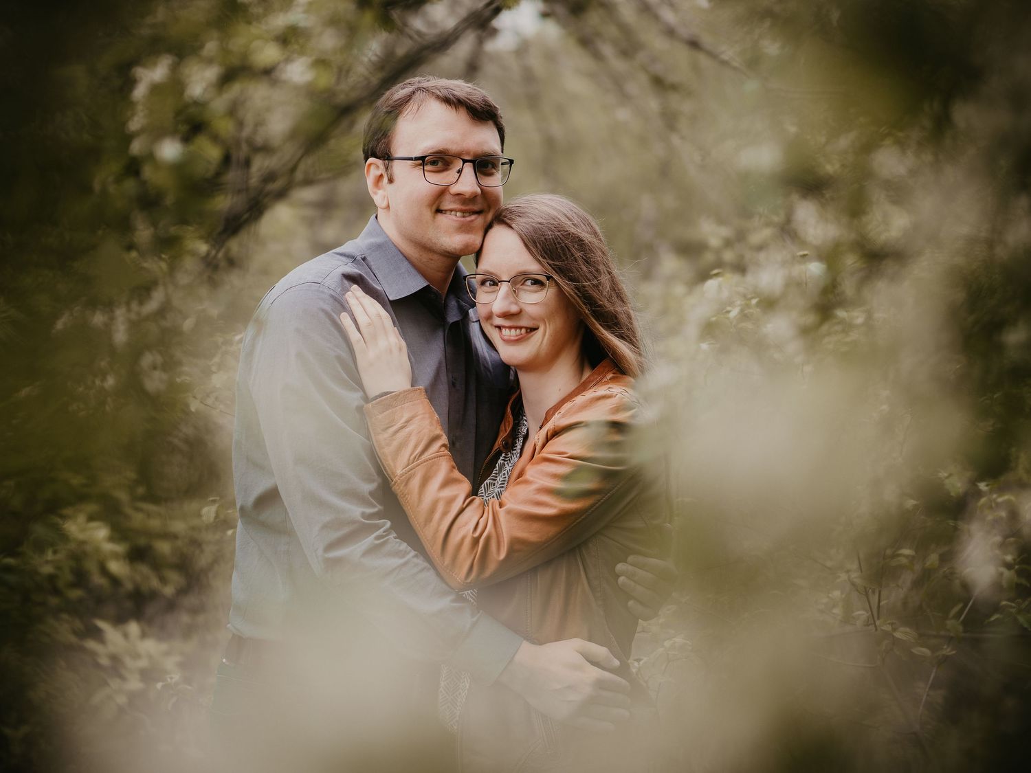 A romantic couple shares tender moments in a natural outdoor setting with soft bokeh lighting effects.