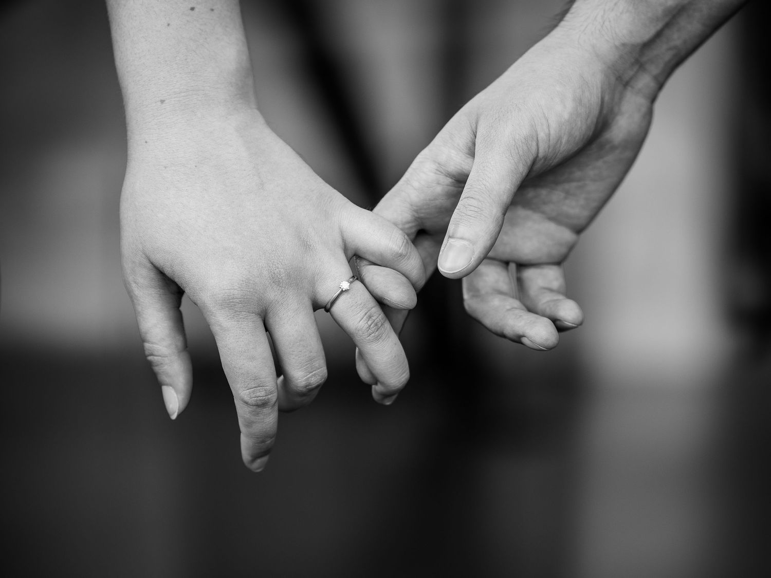 A black and white close-up of two hands reaching out and touching fingers together in an intimate gesture.