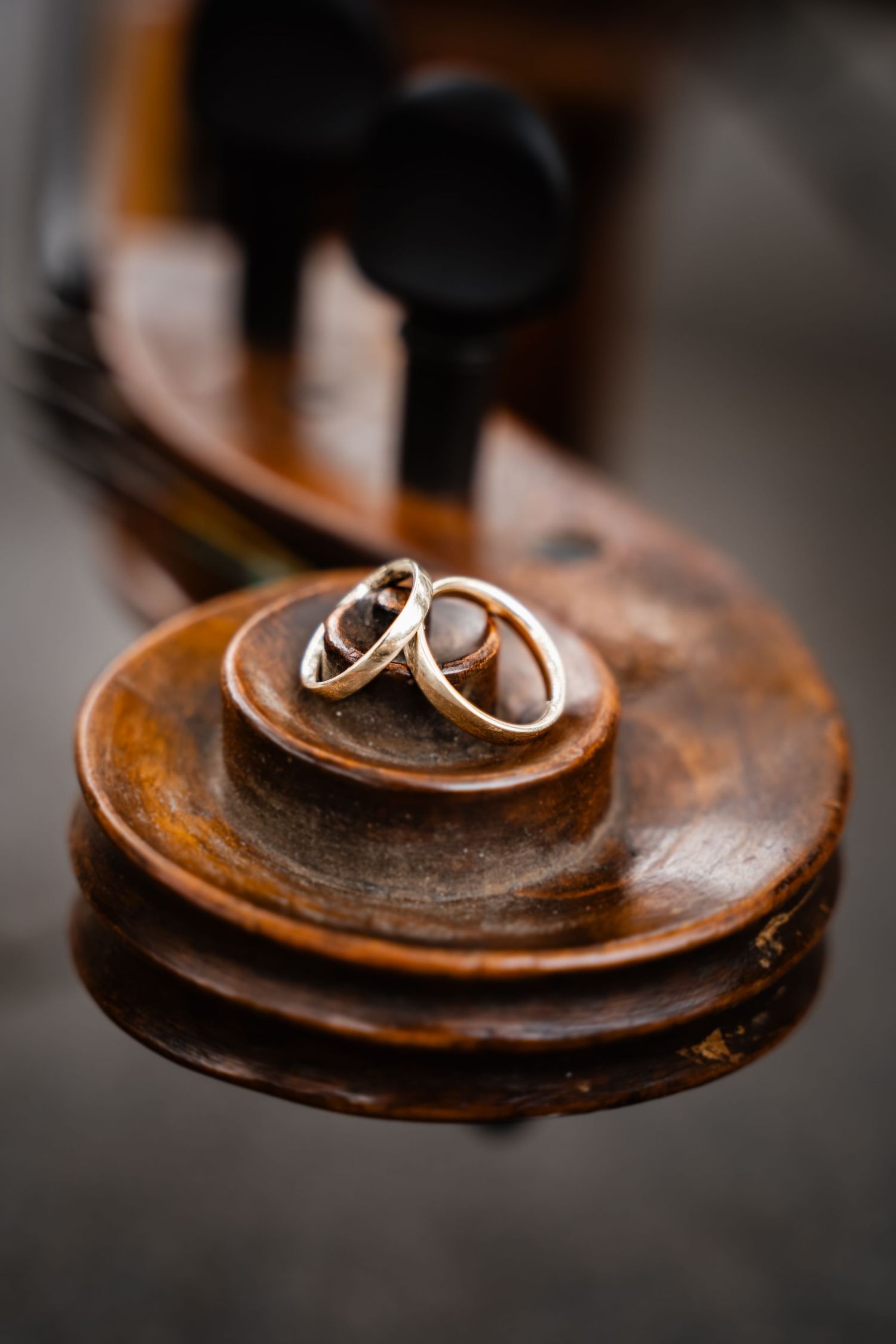 Two gold wedding rings resting on the scroll of a vintage wooden violin or cello.