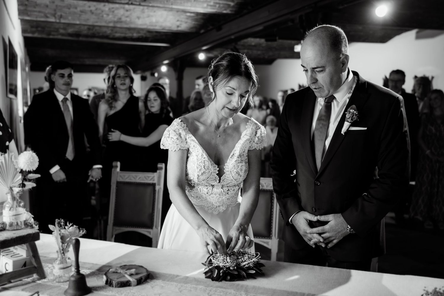Bride and groom stand together at a table during their wedding ceremony in a rustic venue.