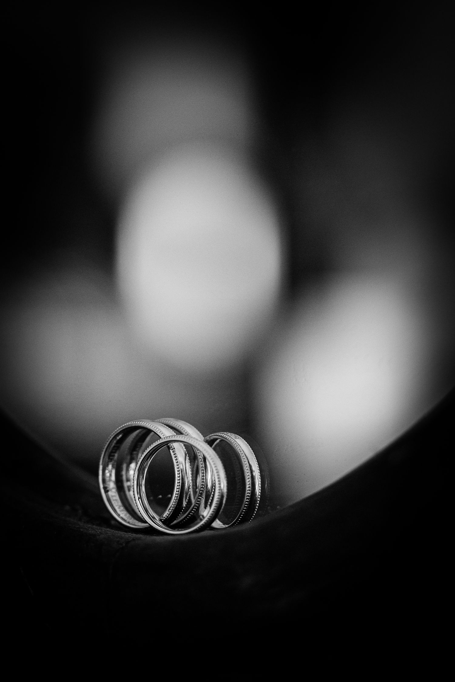 Black and white close-up of two wedding rings resting together with soft bokeh background.