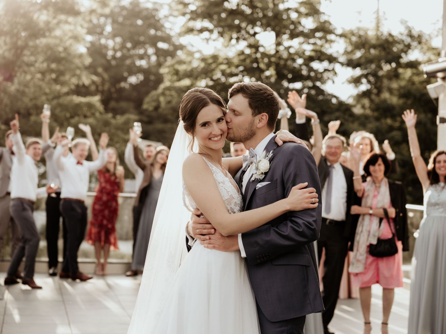 Outdoor wedding celebration with guests watching as couple dances on a waterfront deck.