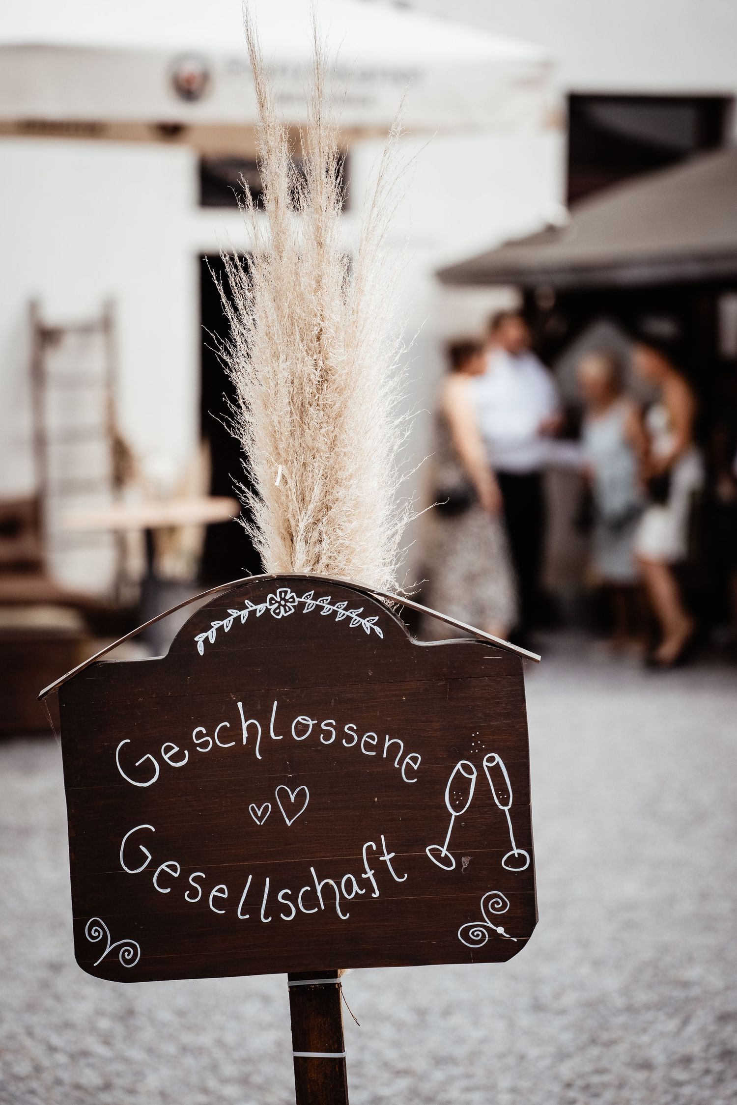 Rustic wooden sign reading Geschlossene Gesellschaft with pampas grass decoration at a private wedding event.