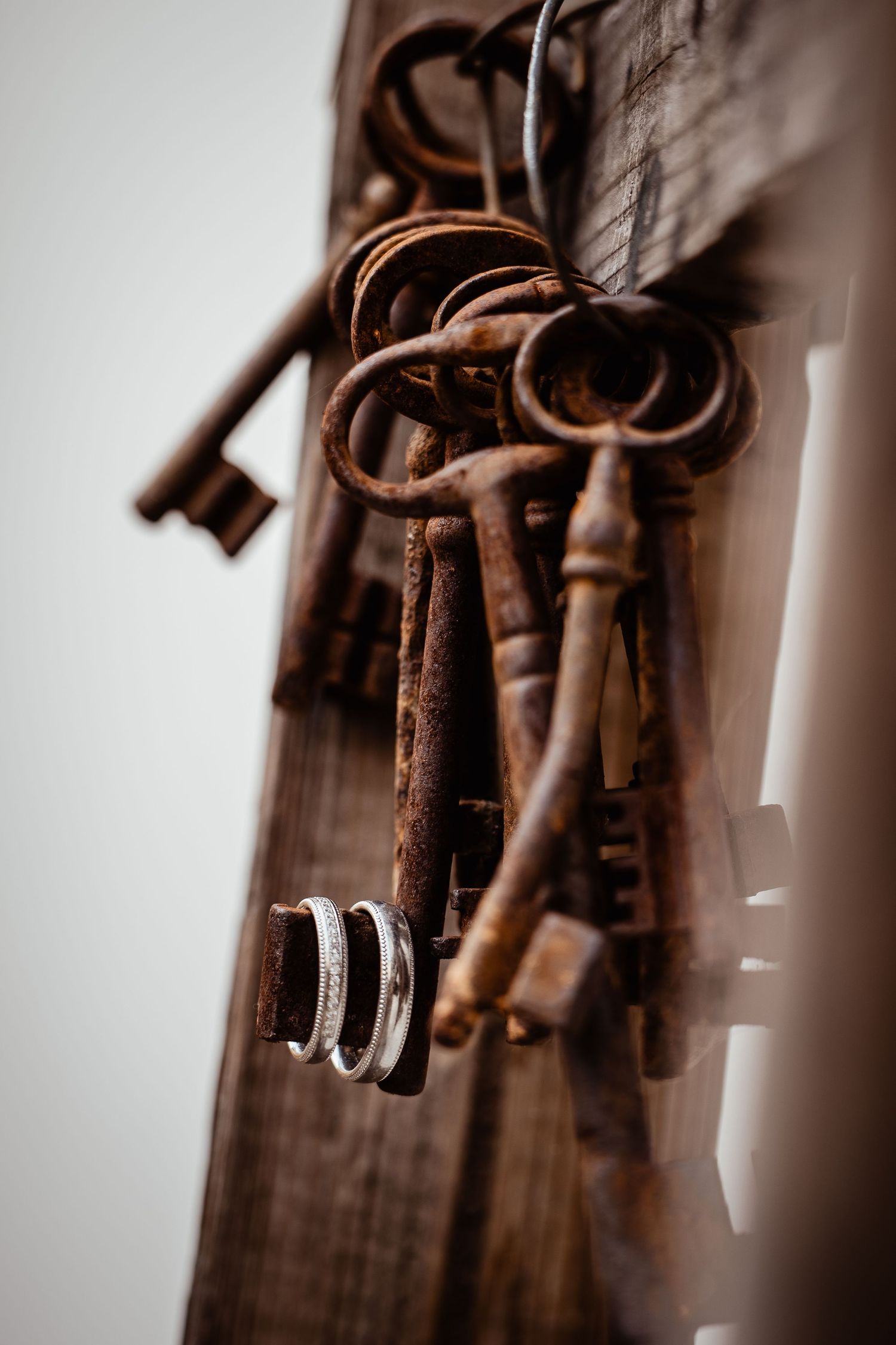 Vintage rusty skeleton keys displayed on wood with wedding rings.