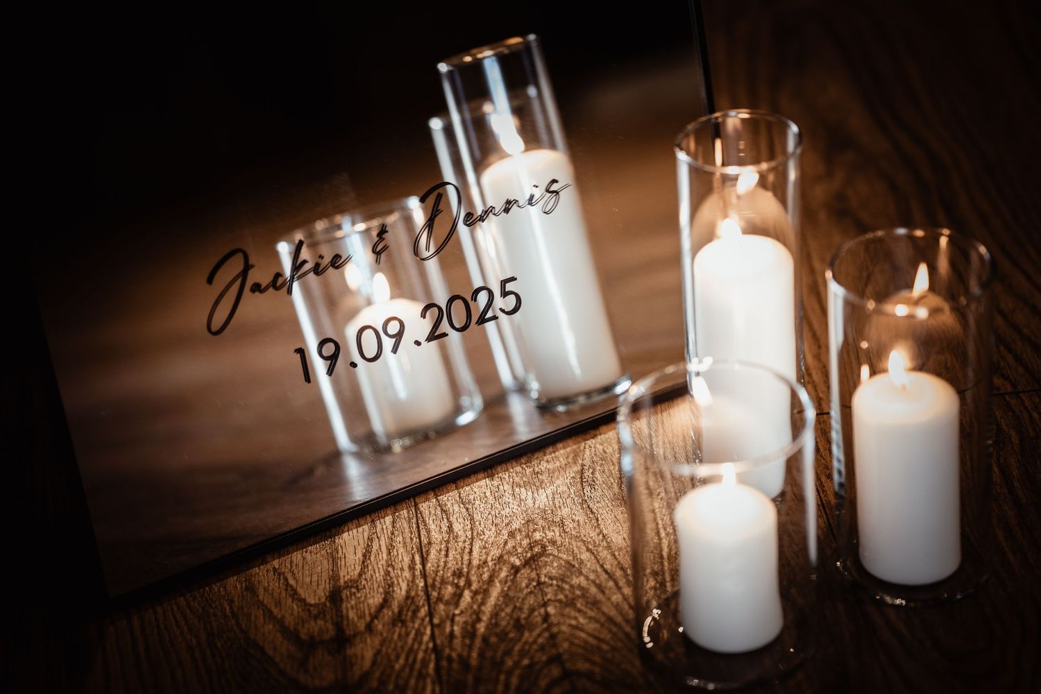 Elegant wedding sign for Jackie and Dennis dated 19.09.2025 surrounded by white pillar candles in glass holders.