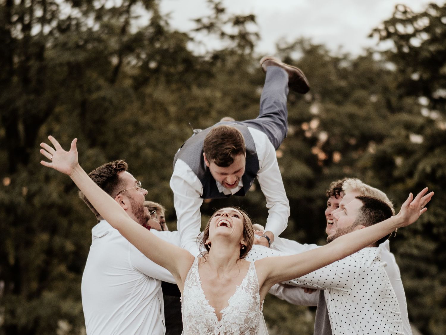 Joyful wedding party celebrates outdoors with arms raised in a candid sequence of celebratory moments.