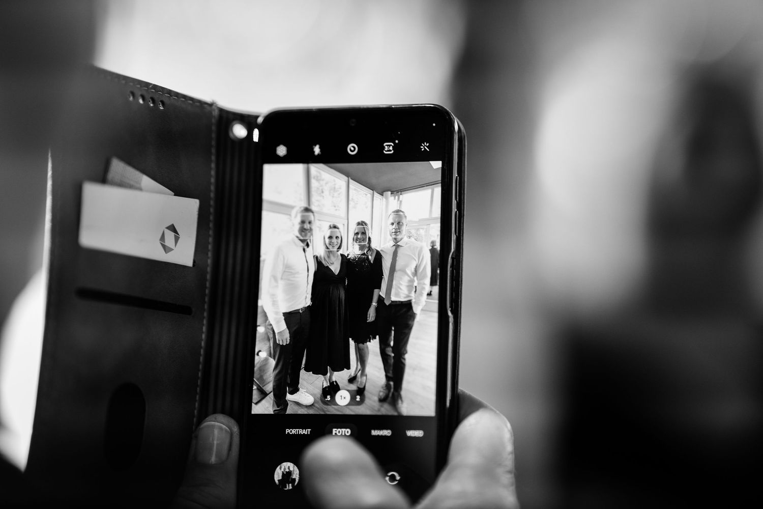 Black and white photo of a smartphone capturing a group of people at an event.
