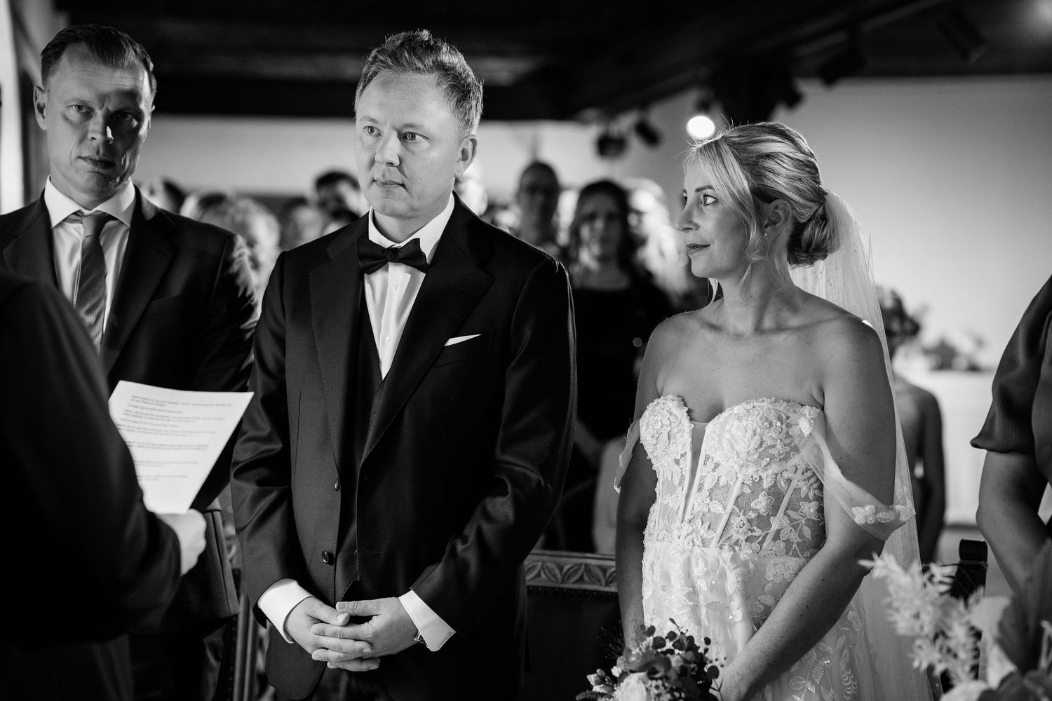 Black and white photo of bride and groom standing at wedding ceremony altar.