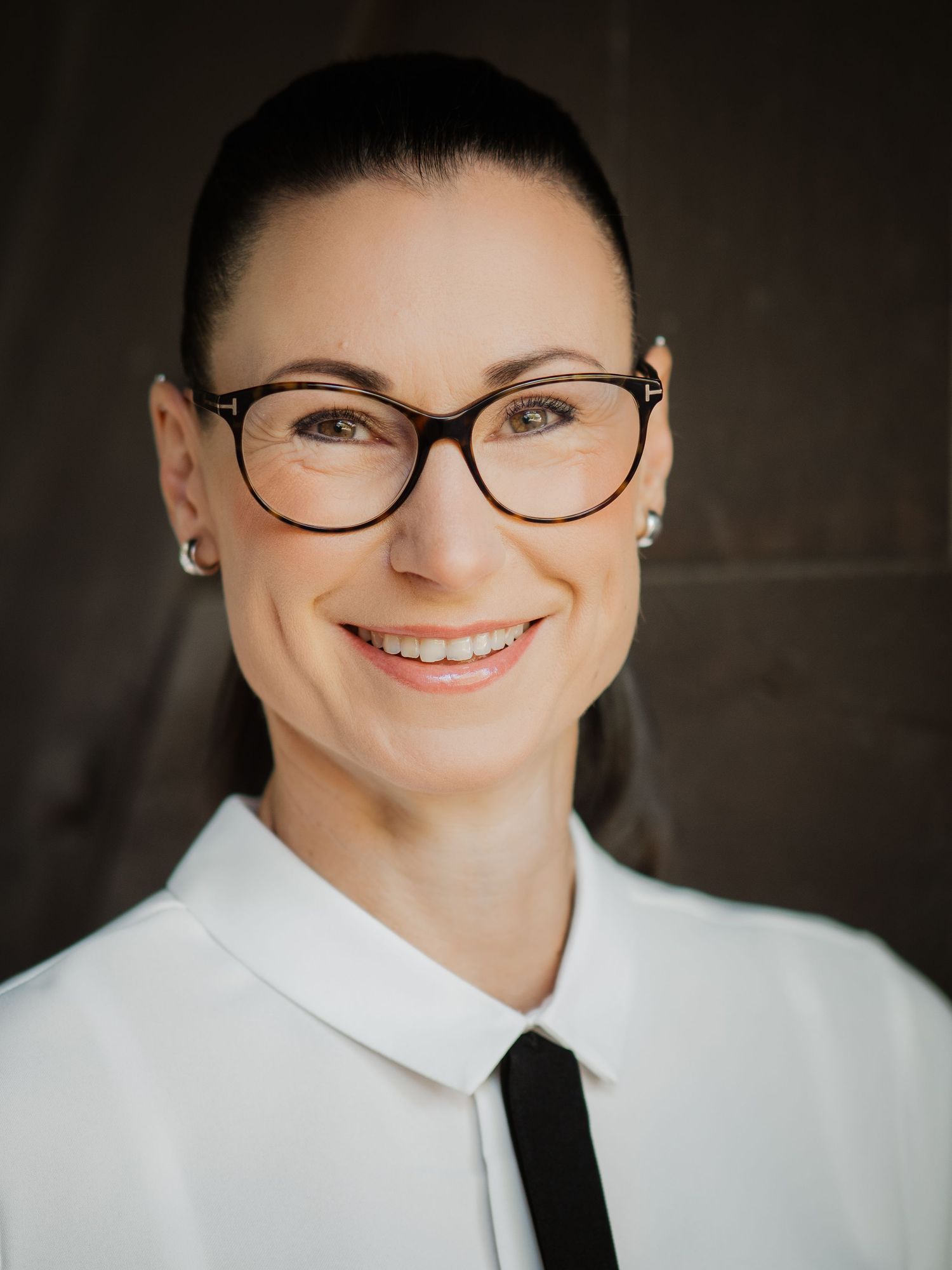 Professional portrait wearing glasses and white shirt with black tie.