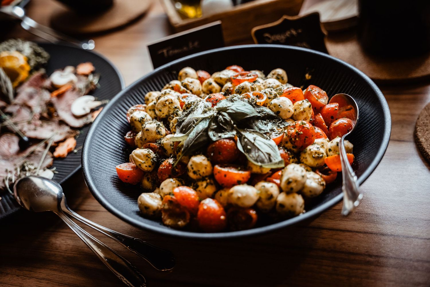 Elegant bowl of roasted gnocchi with cherry tomatoes and fresh herbs served at wedding reception.