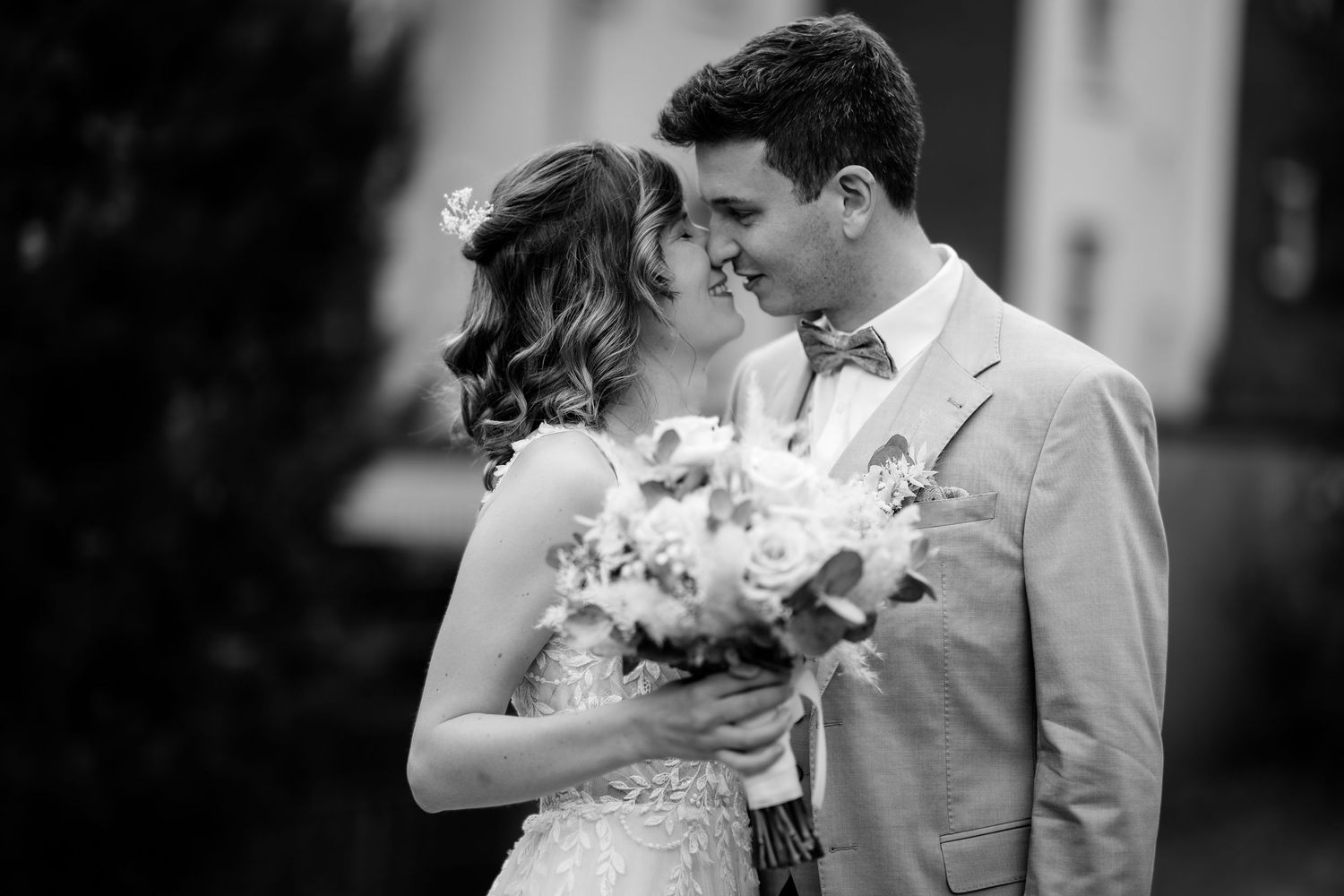 Black and white wedding photo of bride and groom sharing a romantic moment, bride holding a bouquet.