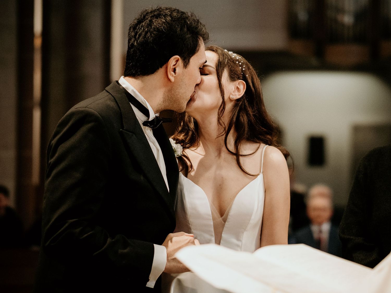 A series of four romantic wedding photos showing couples sharing intimate kisses in an elegant indoor setting.