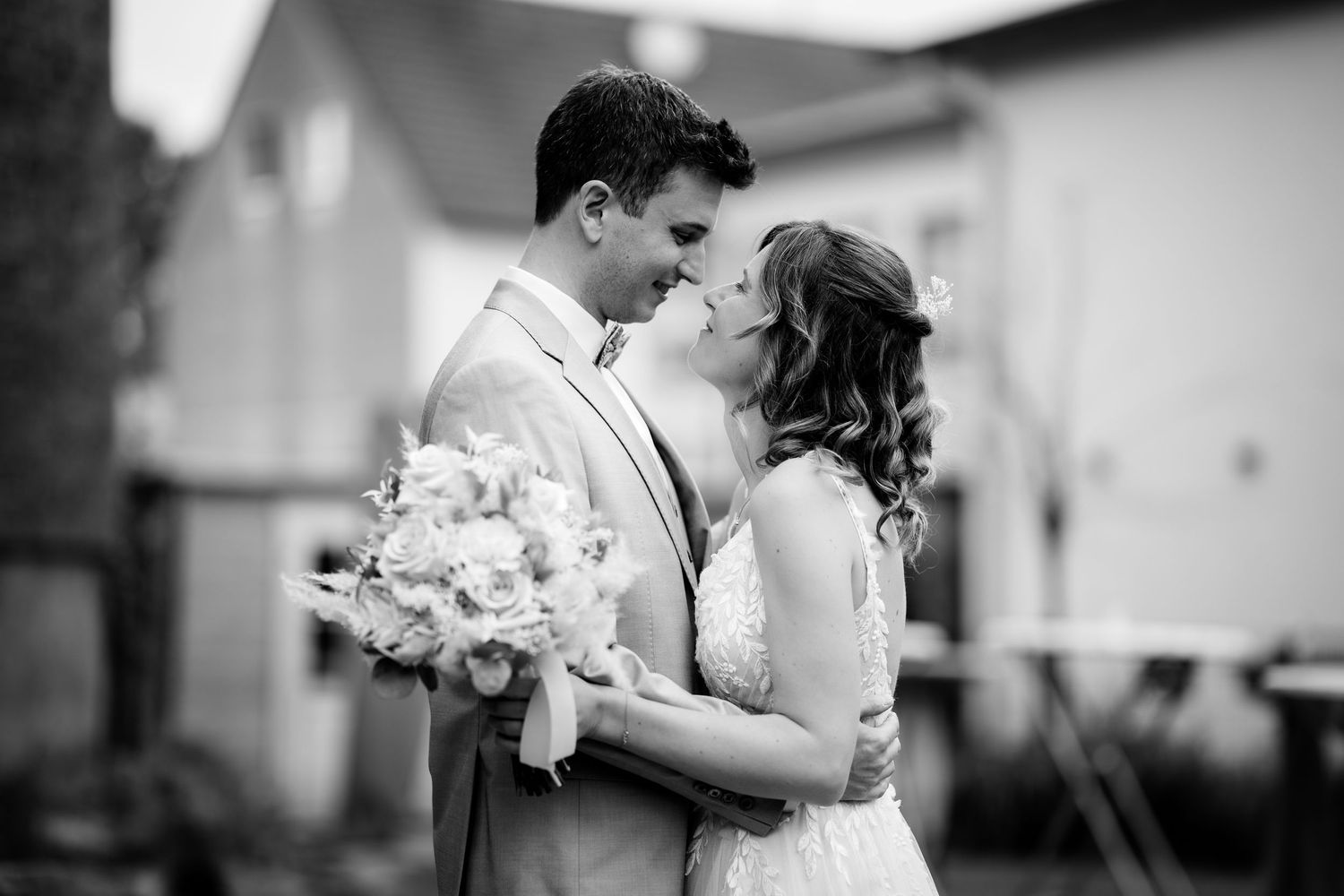 Black and white photo of a bride and groom sharing an intimate moment, bride holding a bouquet.