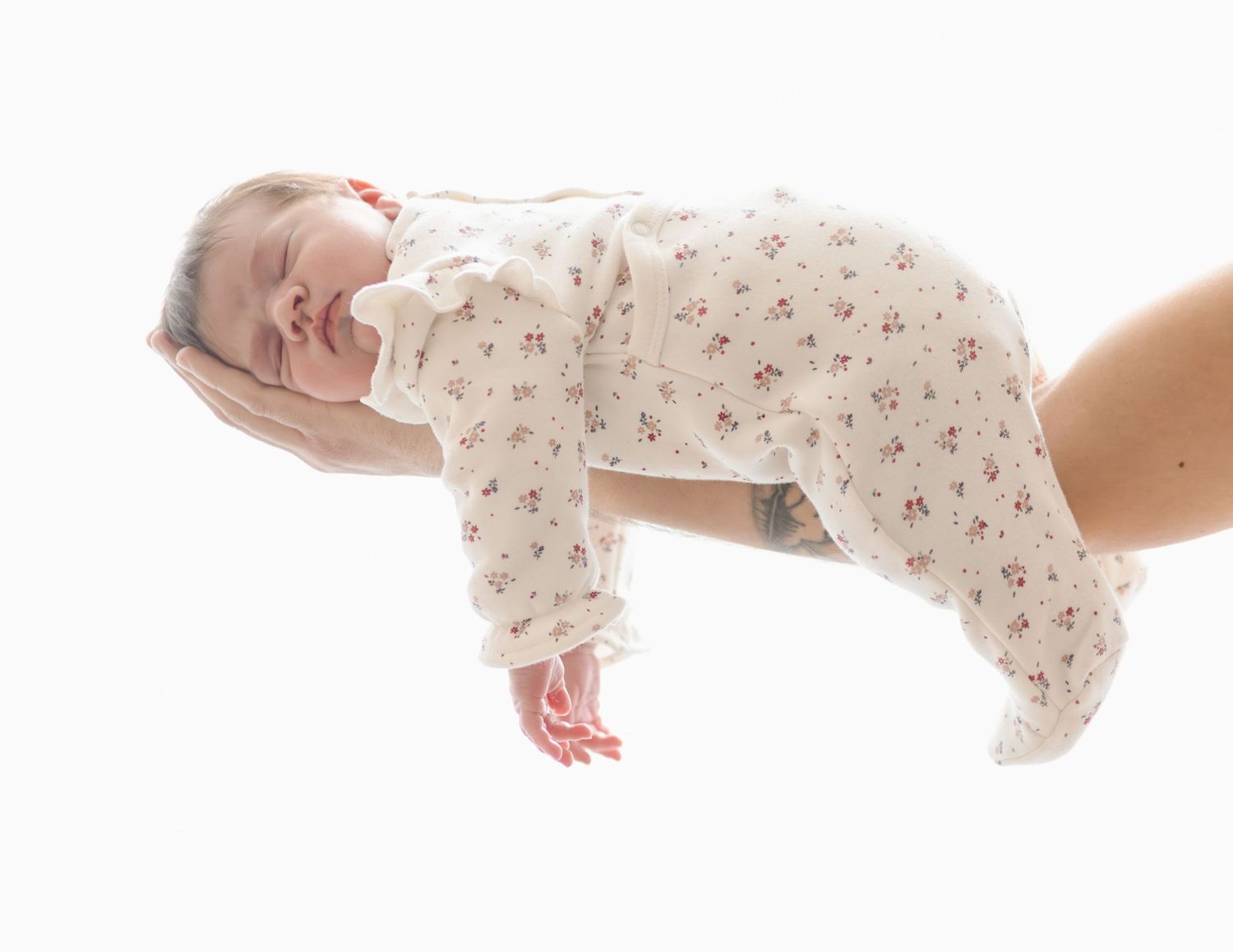 bébé allongé dans les bras de ses parents, séance naissance naturelle dans le studio à L'Arbresle ( ouest lyonnais)