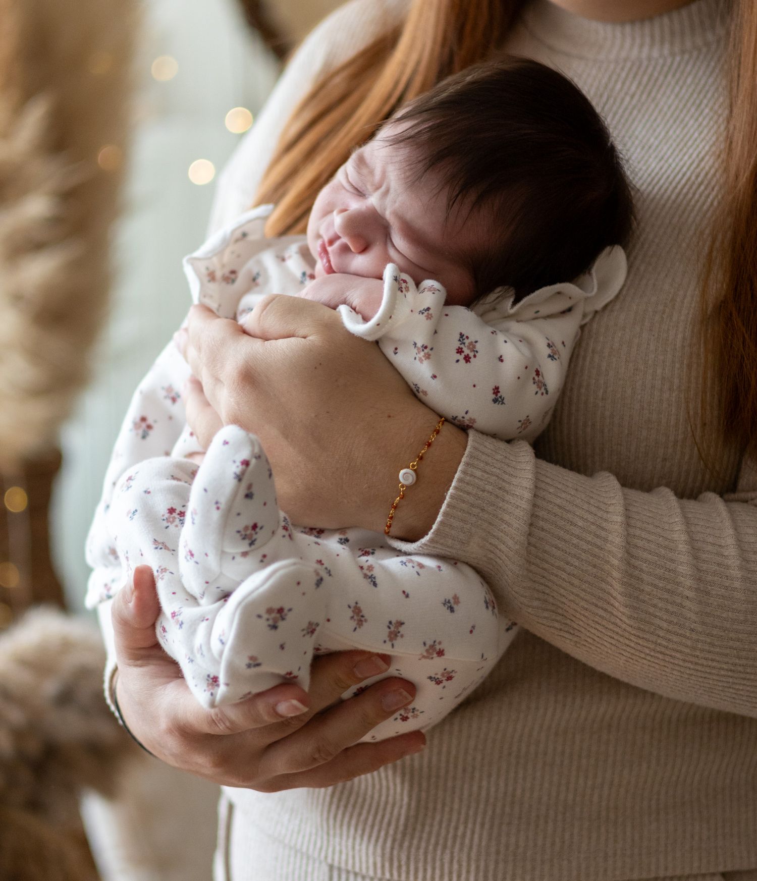 Bébé dans les bras de sa maman, séance naissance naturelle dans le studio à L'Arbresle ( ouest lyonnais) en lumière douce.