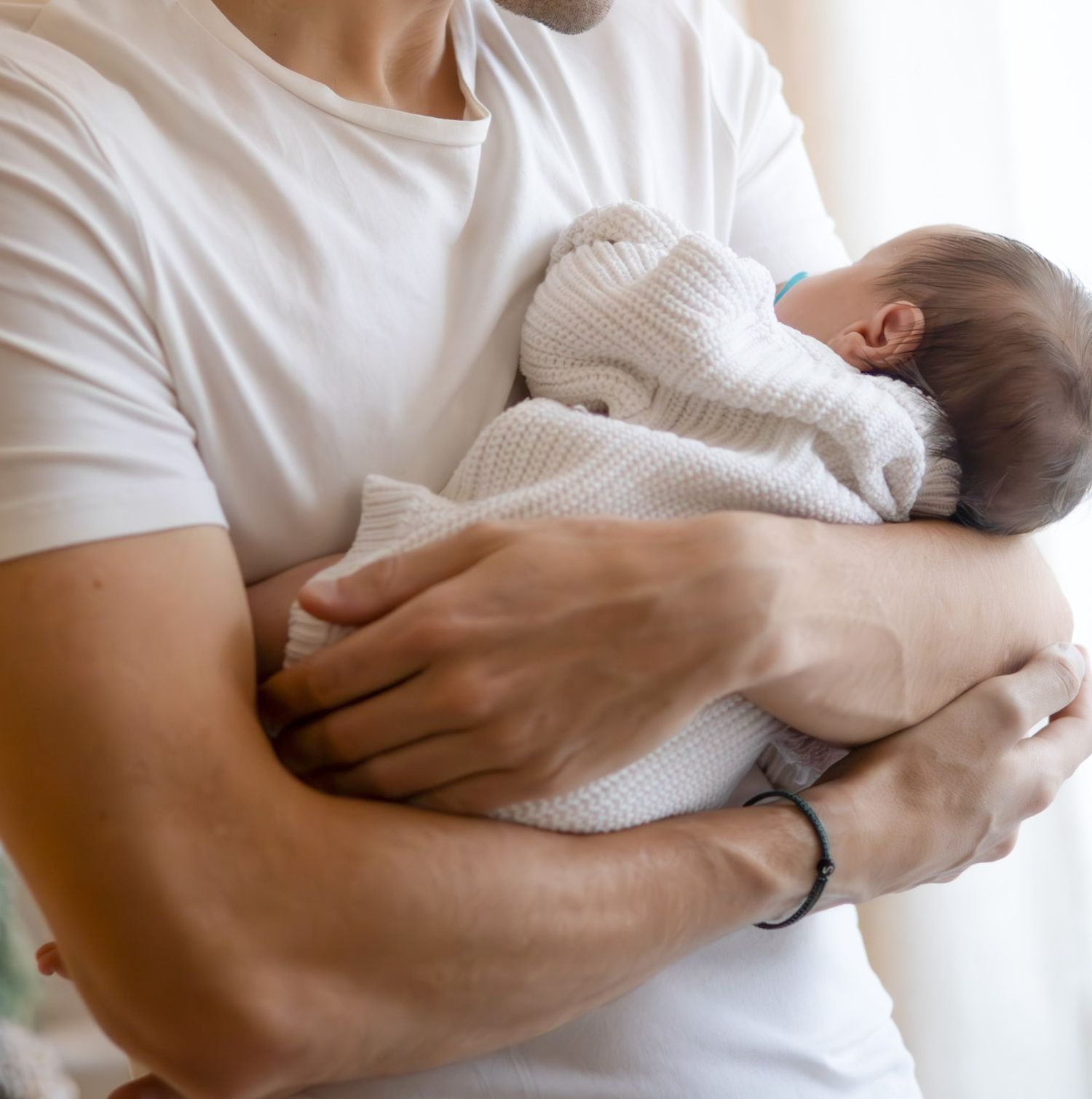 Bébé dans les bras de son papa, séance naissance naturelle à L'Arbresle ( proche de Lyon), moment de tendresse.