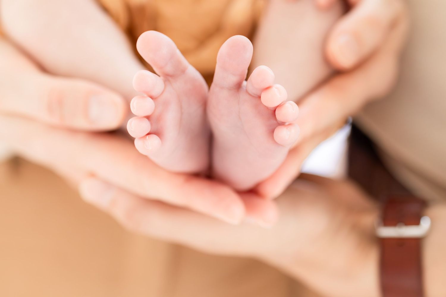 Parents gently cradling their newborn baby's tiny feet in their hands, symbolizing love and new life.