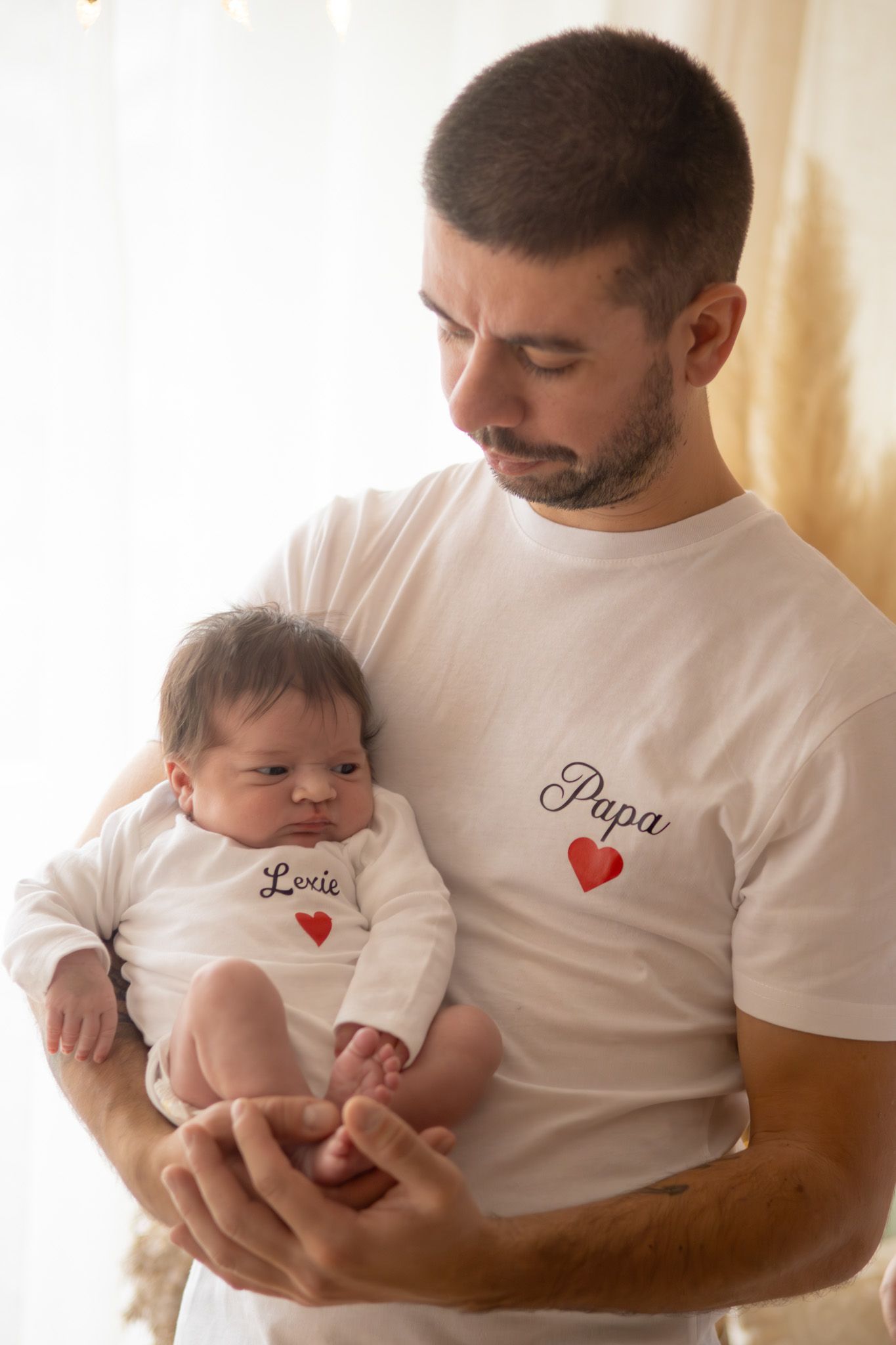 Papa avec son bébé dans les bras, séance naissance naturelle dans le studio à L'Arbresle ( ouest lyonnais) en lumière douce.