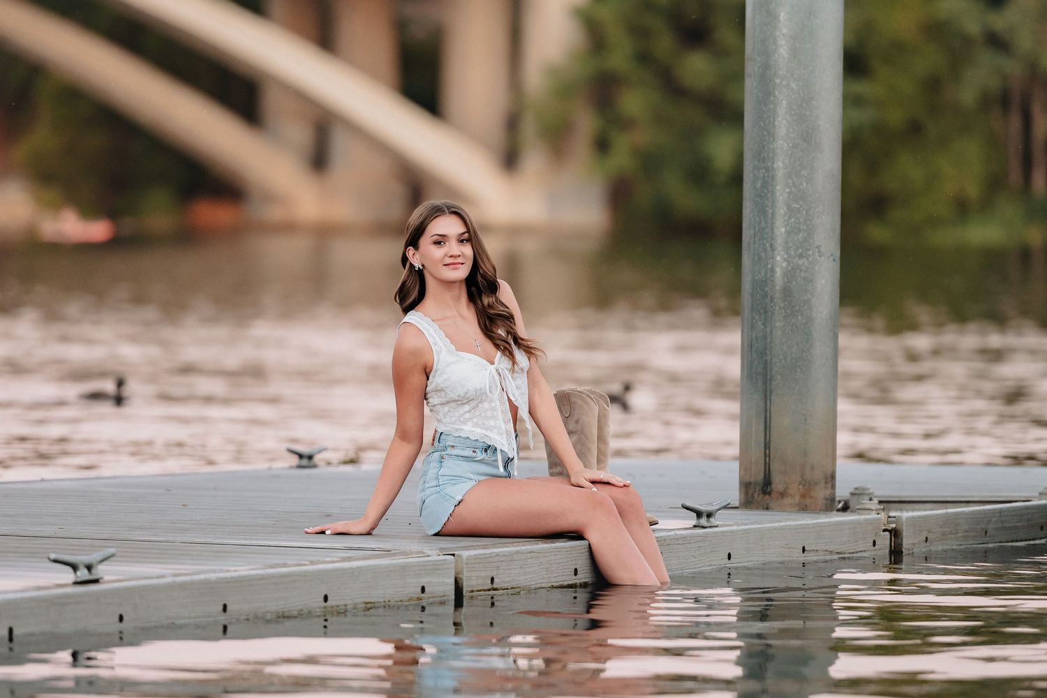 A senior girl sitting on the dock at Black Miner's Bar in Folsom, California