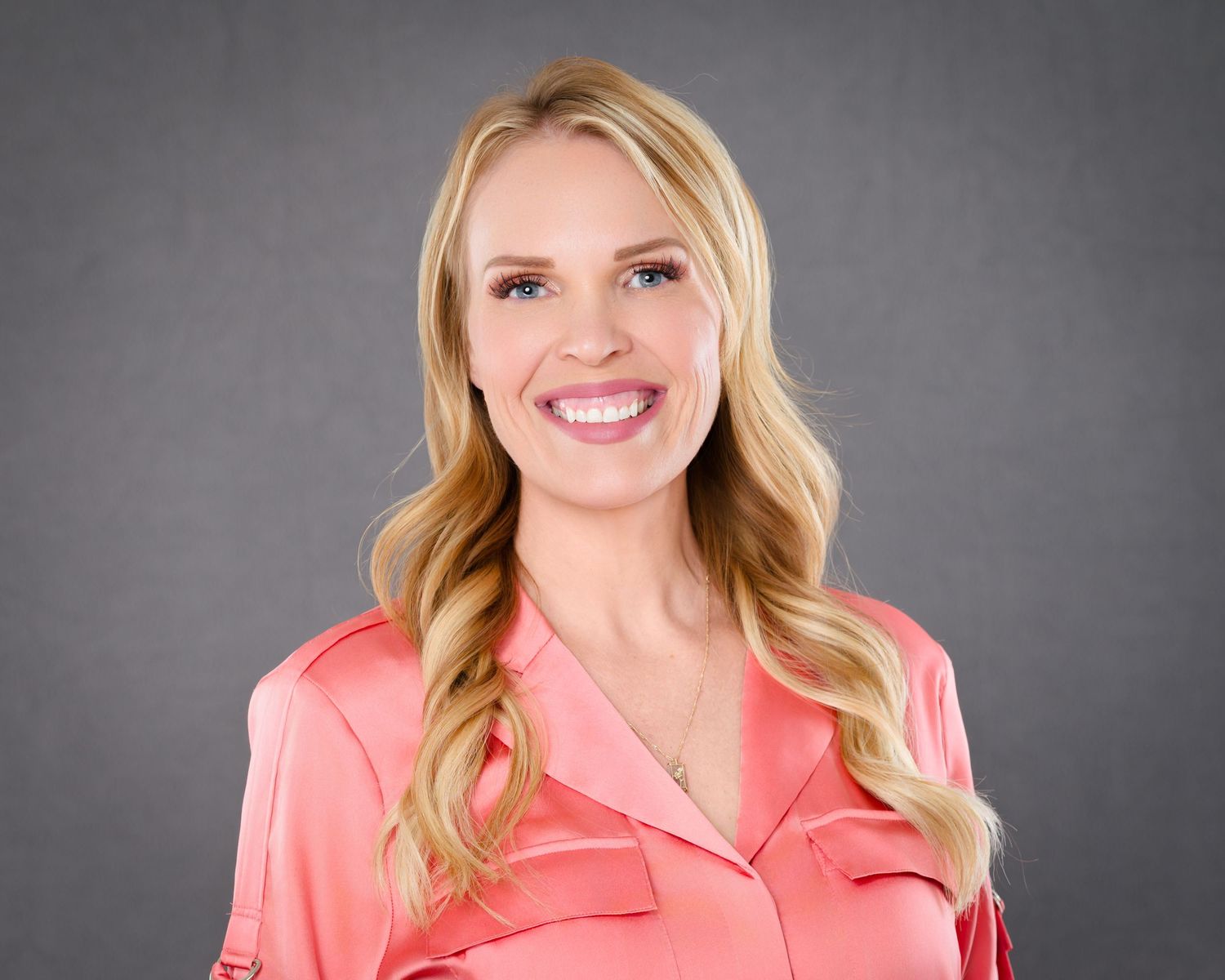 Headshot of a blonde woman against a grey backdrop