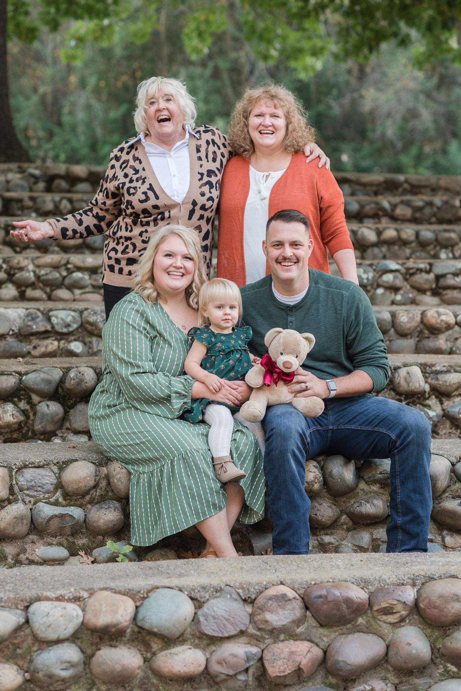 A family photo with parents, baby, grandma, and great grandma.  Great grandma is laughing and very animated.