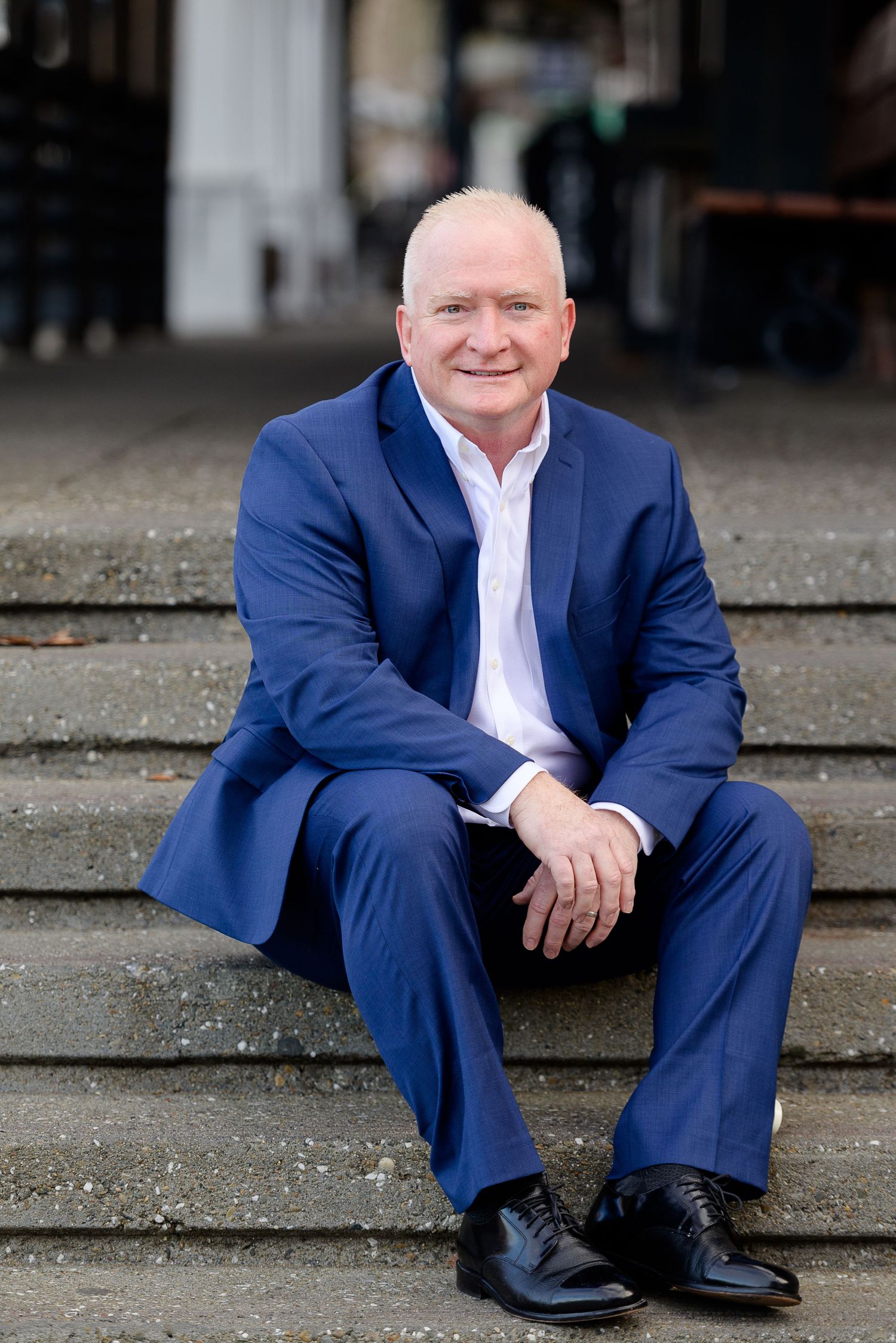 Realtor sitting on concrete steps, wearing a blue suit