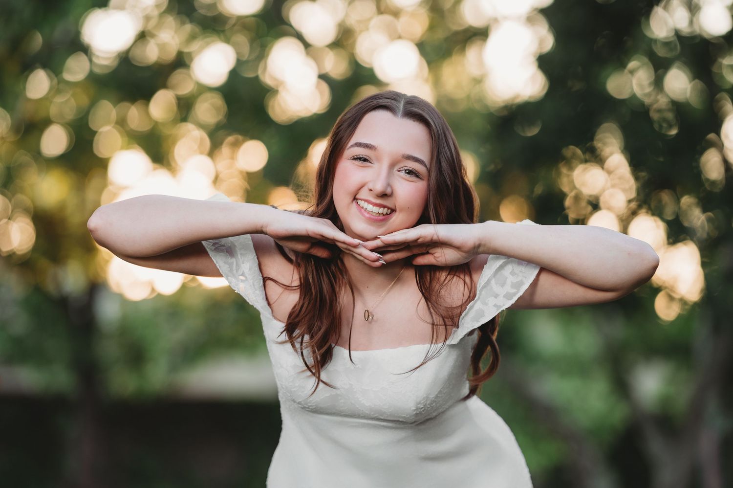 A senior girl make a fun pose with her hands under her chin taken in Citrus Heights, California