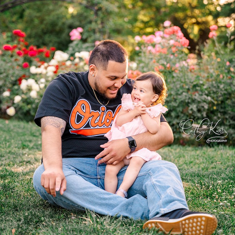 Father and toddler daughter sitting on the ground at McKinley rose garden
