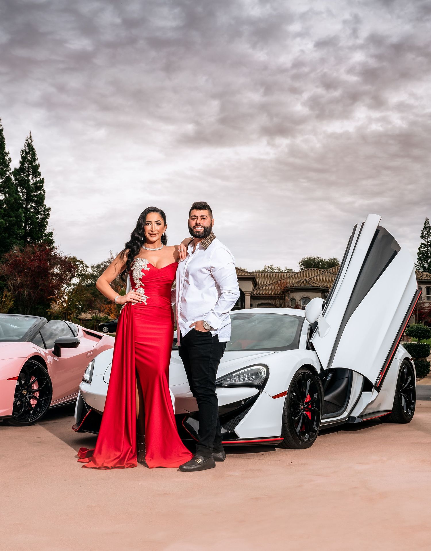 Luxury couple posed in front of their lambourginis