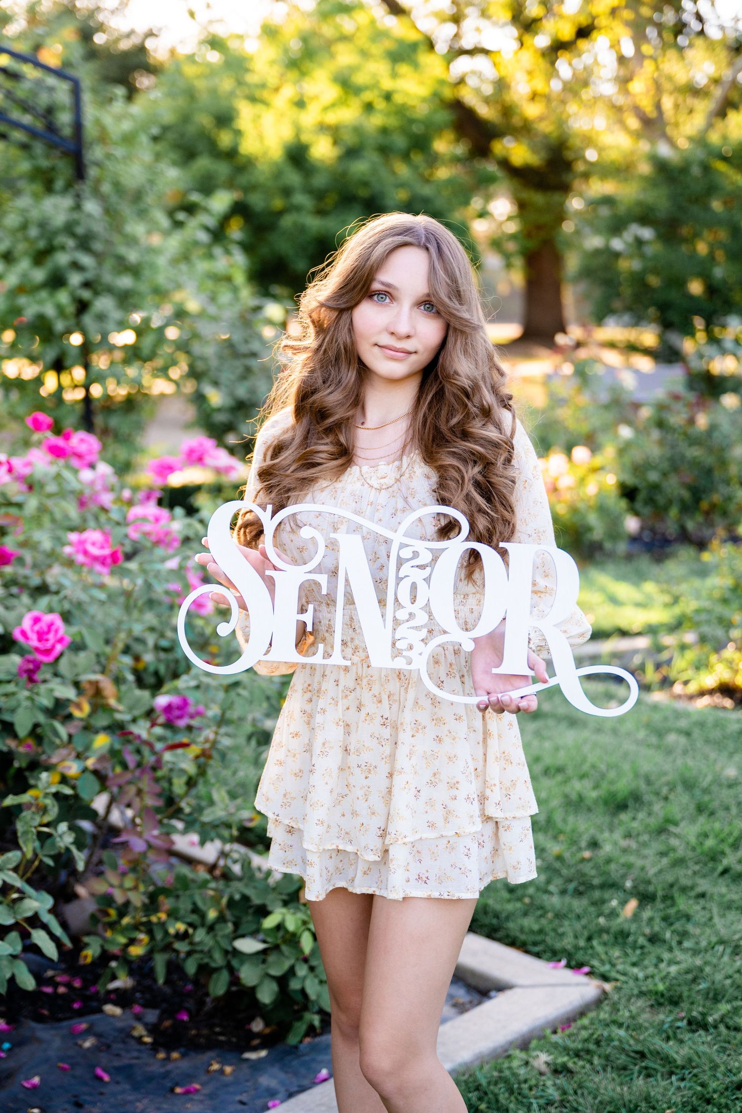 High school senior girl holding a senior sign at McKinley Rose Garden in Sacramento, California