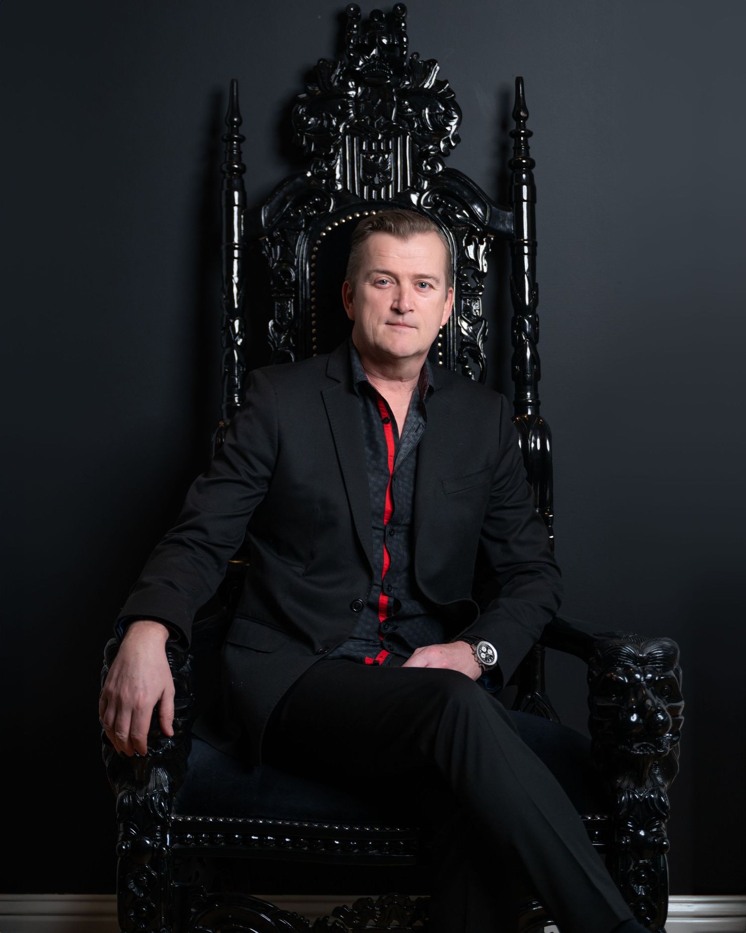 personal branding - a gentleman sitting on a black throne like chair against a black wall