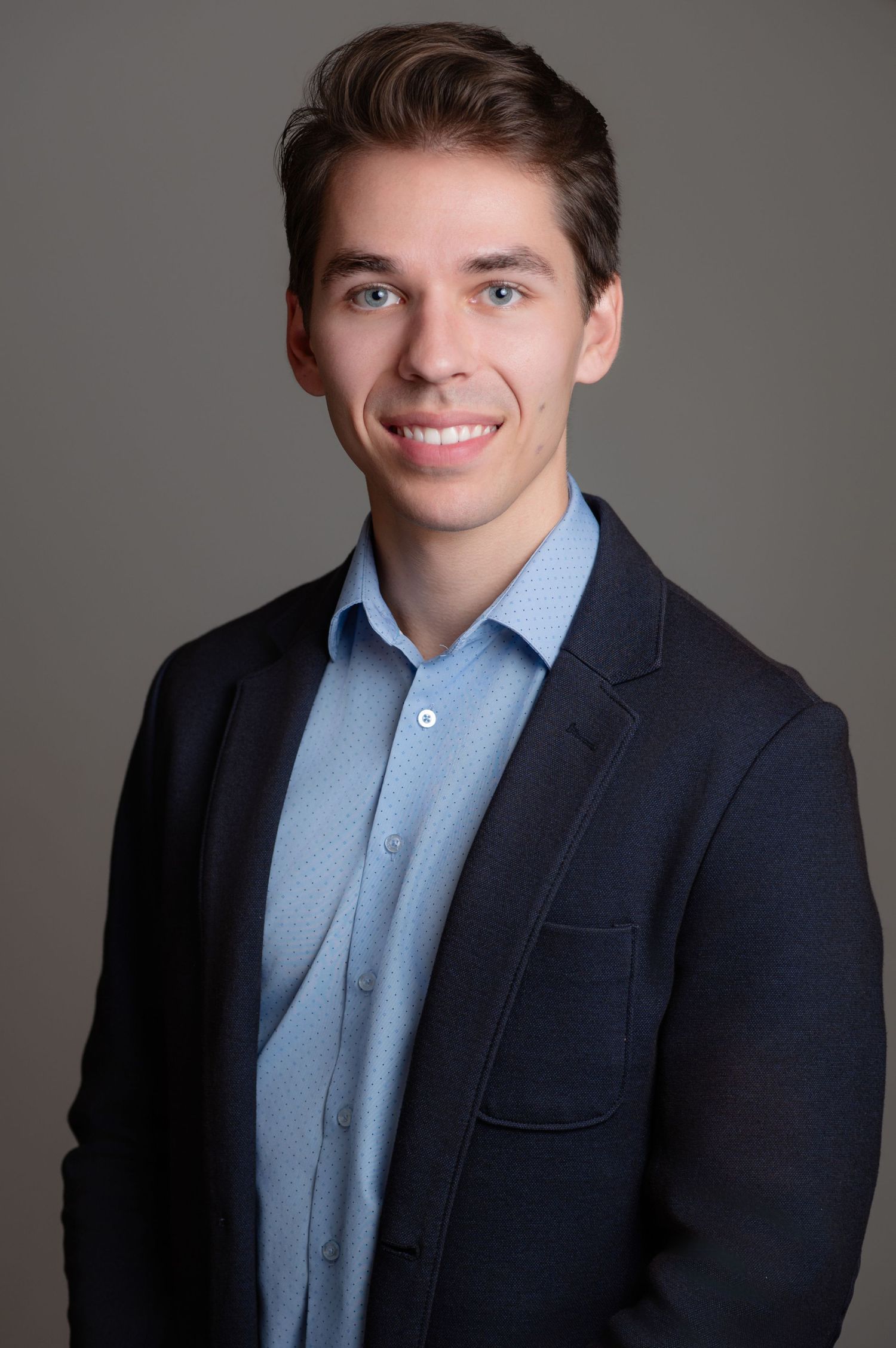 headshot of a gentleman in a navy jacket and blue button down shirt