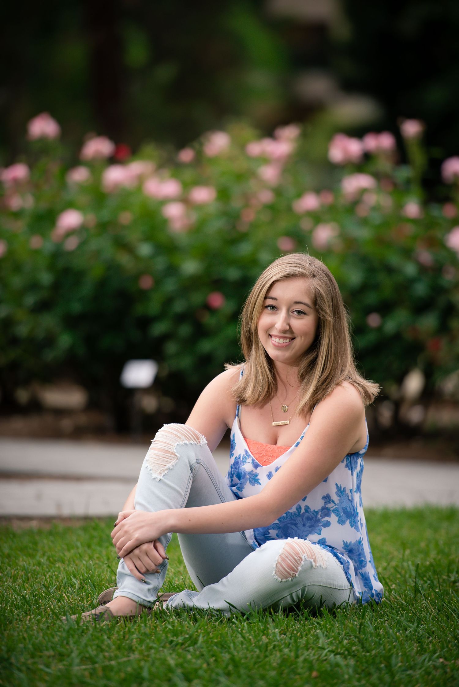 A Senior girl sitting on the lawn in front of the California State Capitol rose garden in Sacramento, California