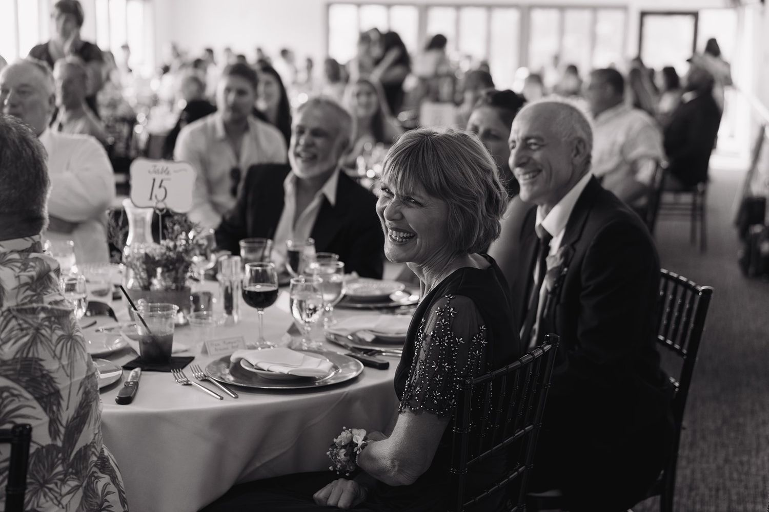 Black and white photo of guests seated at tables during a wedding reception celebration.