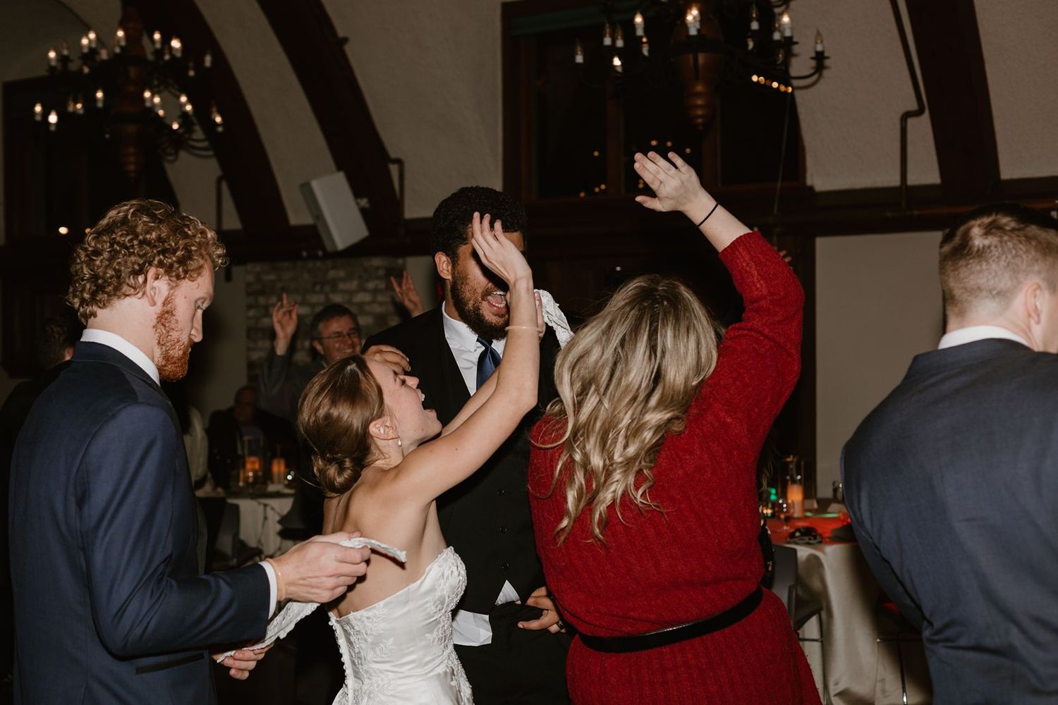 Wedding celebration on dance floor with guests in formal attire.