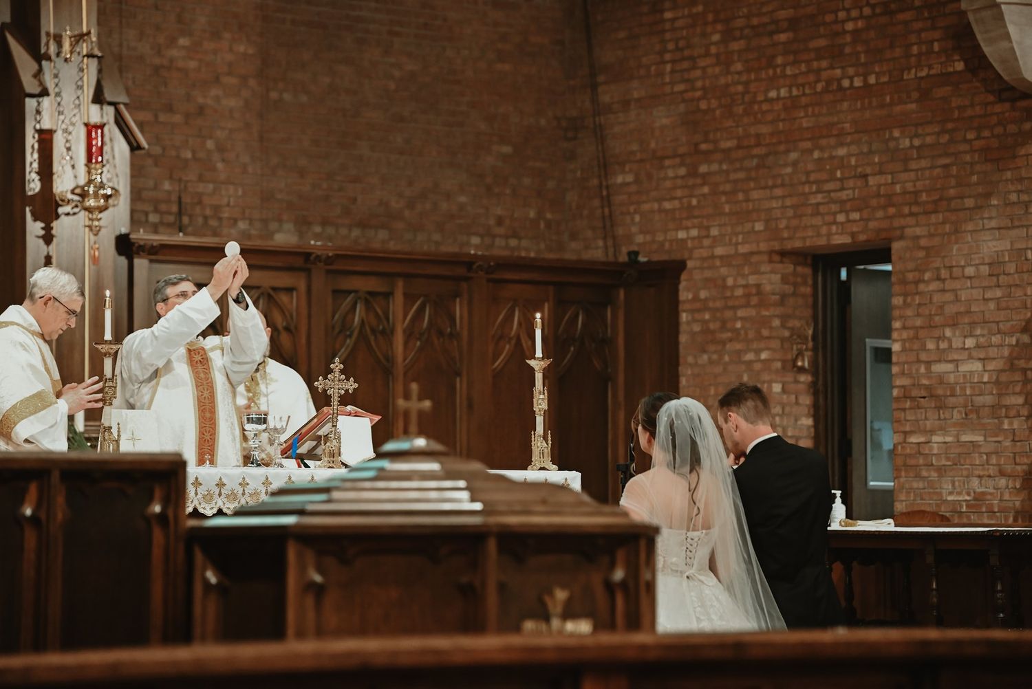 Bride and groom celebrate their first dance together in a rustic brick-walled venue with warm lighting and elegance.