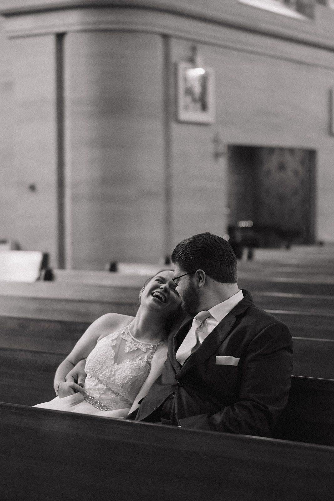 A romantic black and white photograph showing a couple resting together in a church pew.