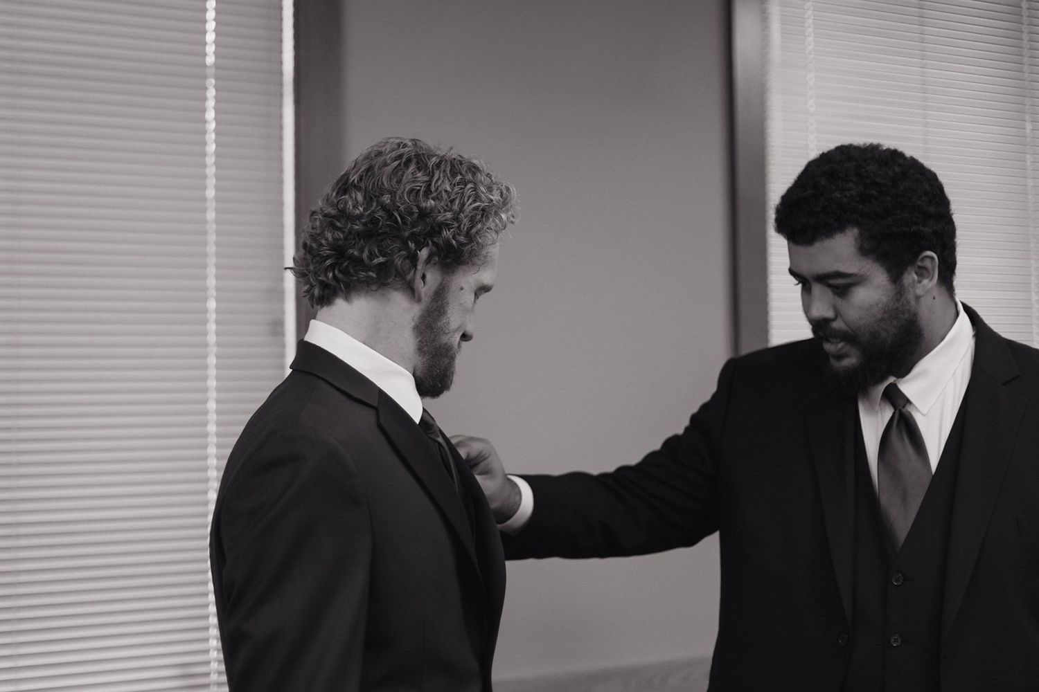 Two men in formal attire having a meaningful interaction in an office setting.