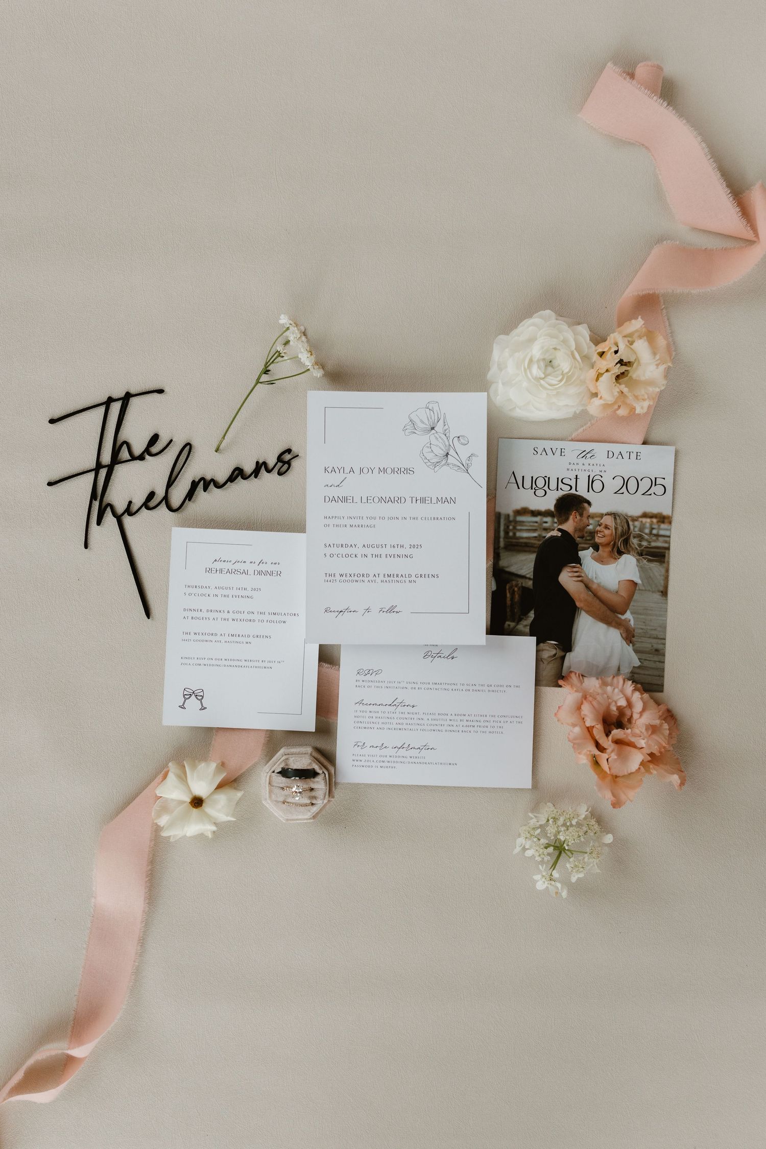 Wedding invitation suite with pink ribbons and dried flowers laid out on neutral background with delicate styling details.