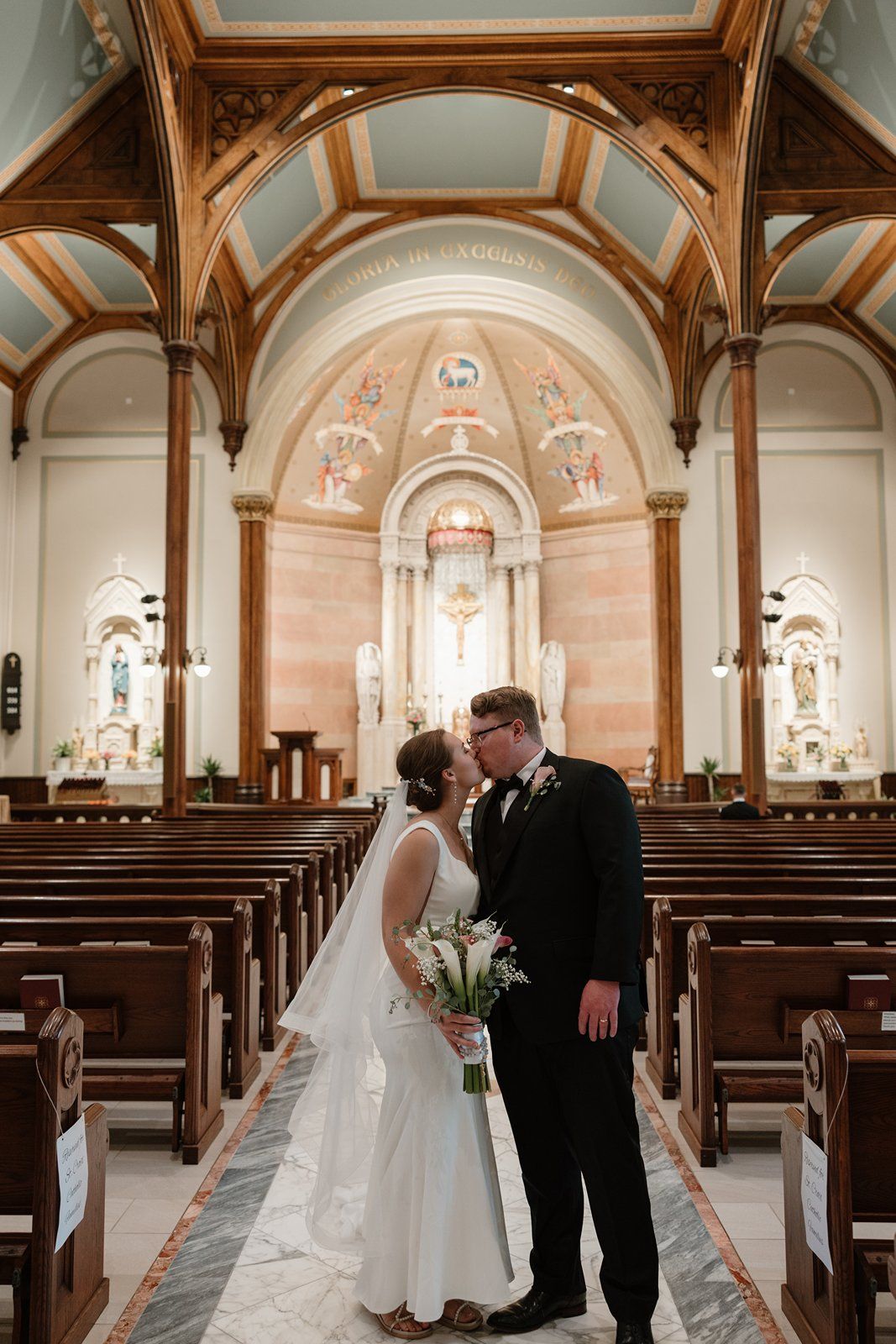 A wedding ceremony in a beautiful Catholic church with ornate architecture and arched ceilings.