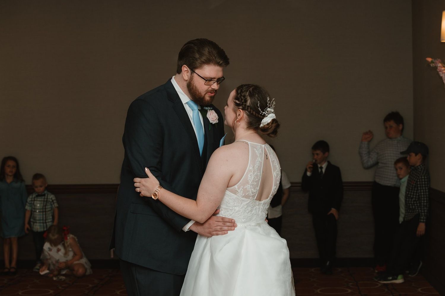 Newlywed couple shares a romantic first dance at their wedding reception in a dimly lit venue.