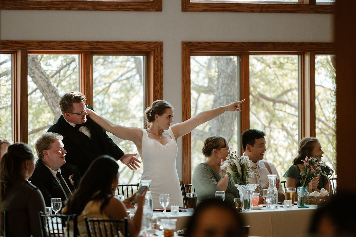 Panoramic view of a rustic restaurant dining room with wooden beams and large windows overlooking nature.