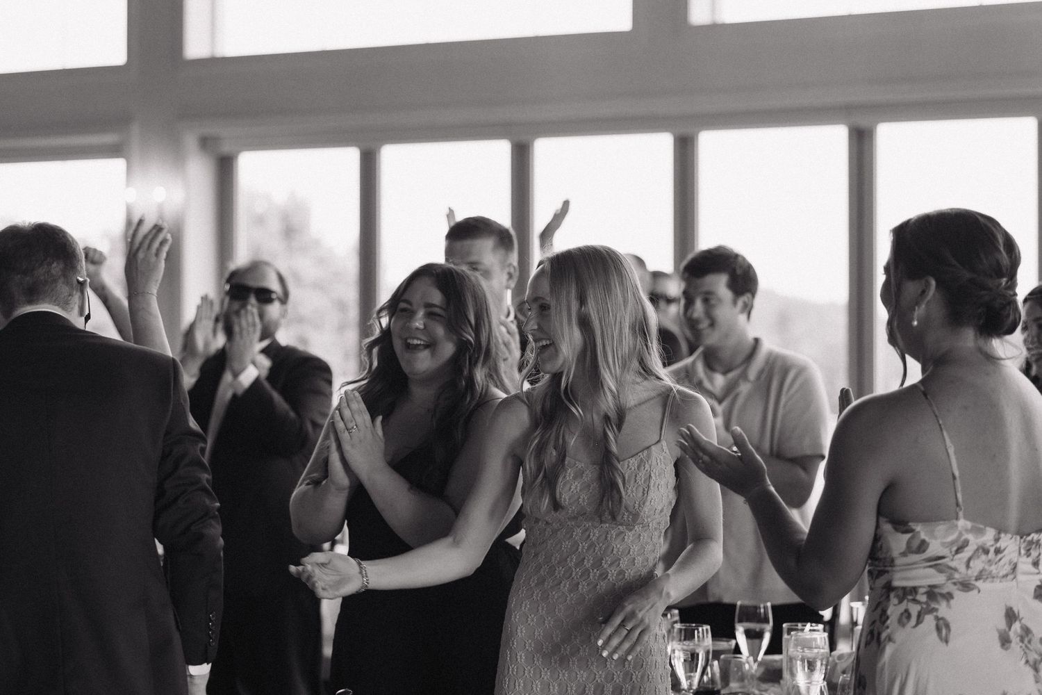 Wedding guests share joyful reactions and laughter during a reception celebration.
